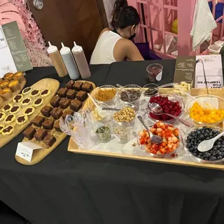 Our topping bar set up for catering: fruit, crunches, drizzles and açaí cups laid out